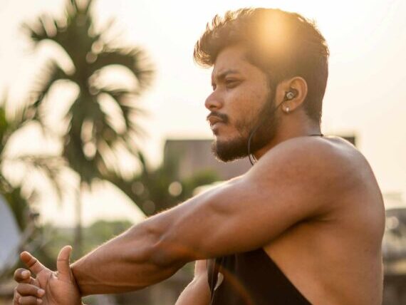Muscular young man stretching outdoors, capturing a warm and vibrant fitness moment.