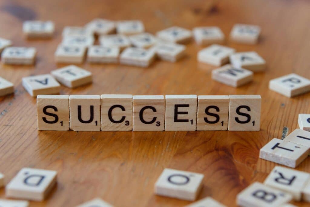 Wooden letter tiles spelling 'success' on a scattered background, symbolizing achievement.