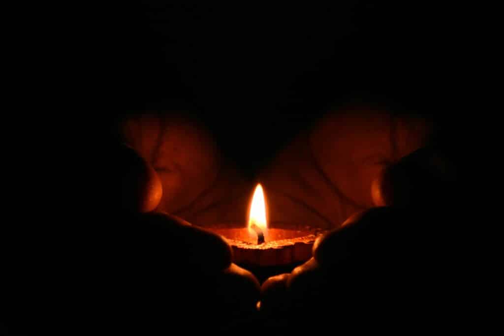 pexels-photo-783200-783200 Close-up of hands warmly embracing a lit candle in the dark, creating a cozy atmosphere.